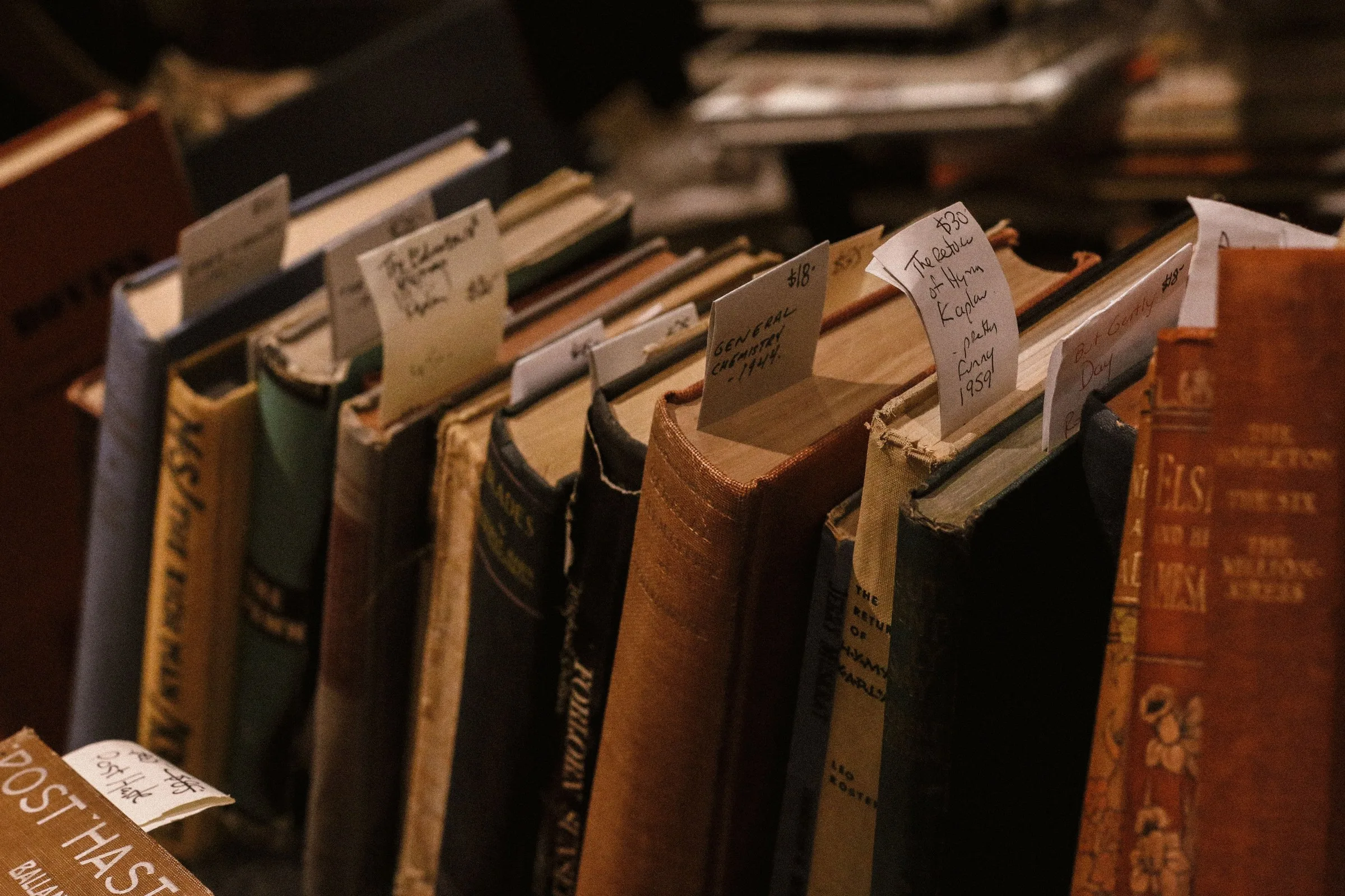 Antique leather-bound books with gilded spines, stacked on a dark shelf